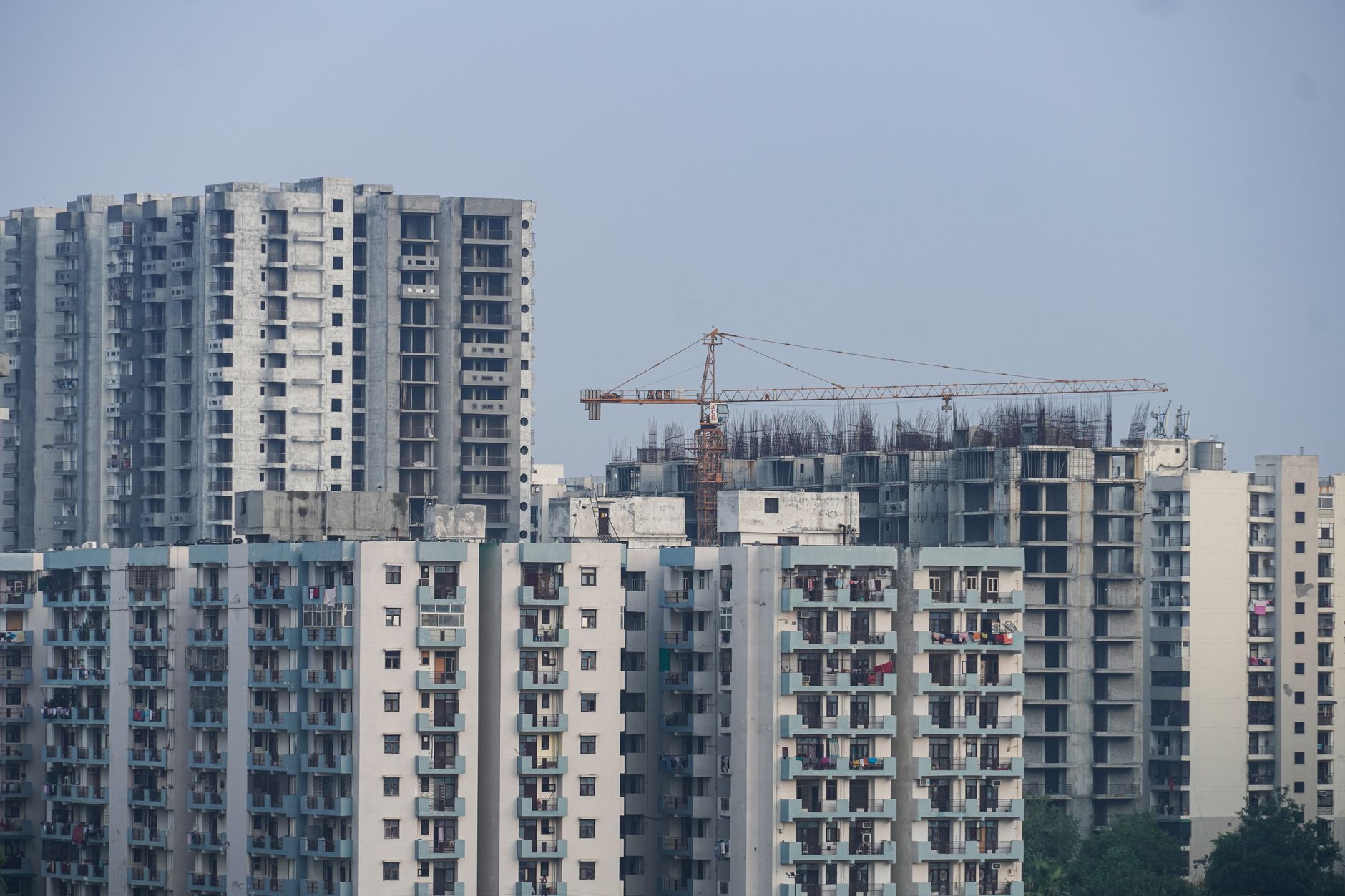 Modern high-rise buildings under construction with cranes in a cityscape.