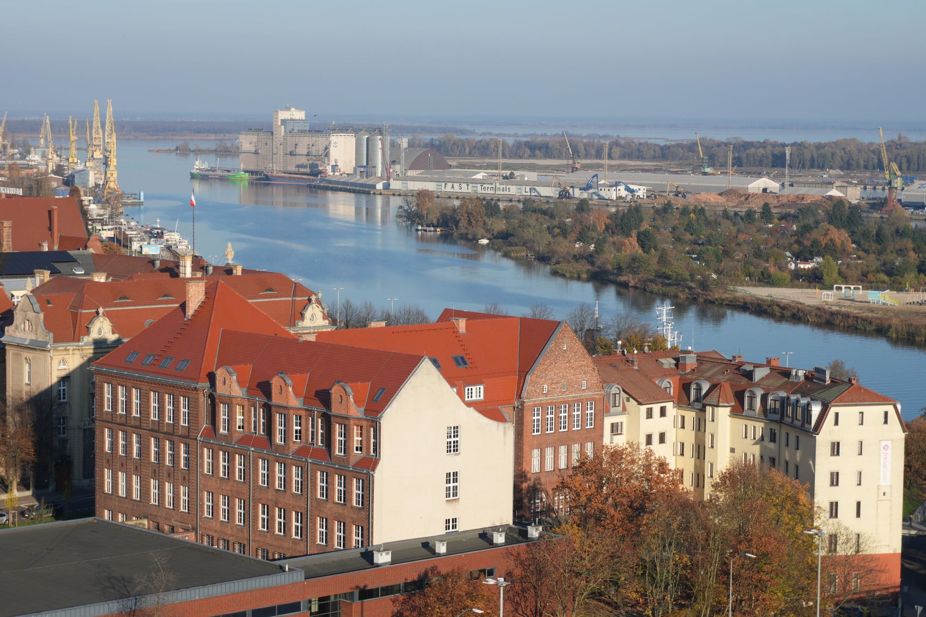 Aerial view of red-roofed buildings and a river landscape in an urban setting.