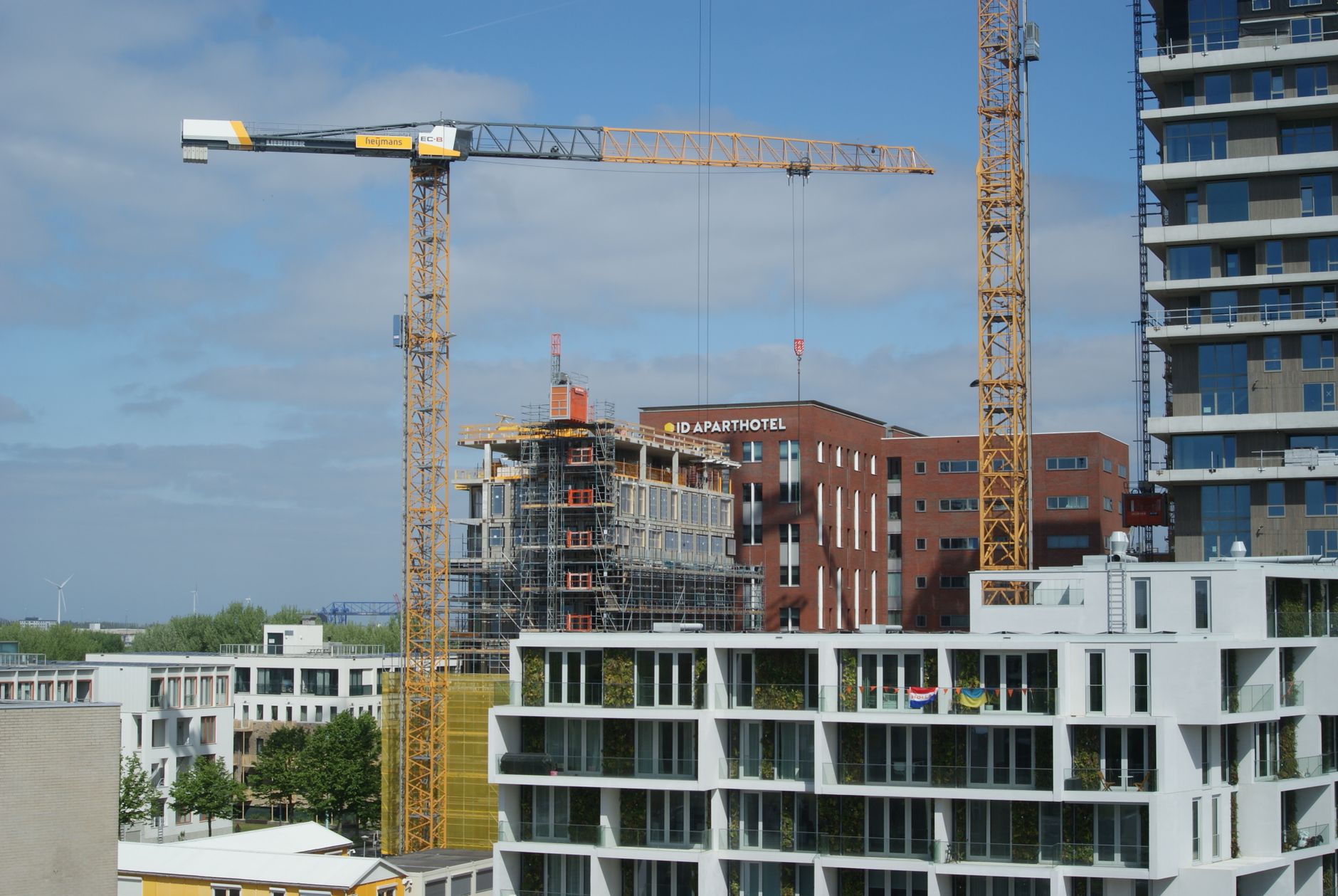 Cityscape featuring construction site with tower cranes and modern buildings under clear sky.