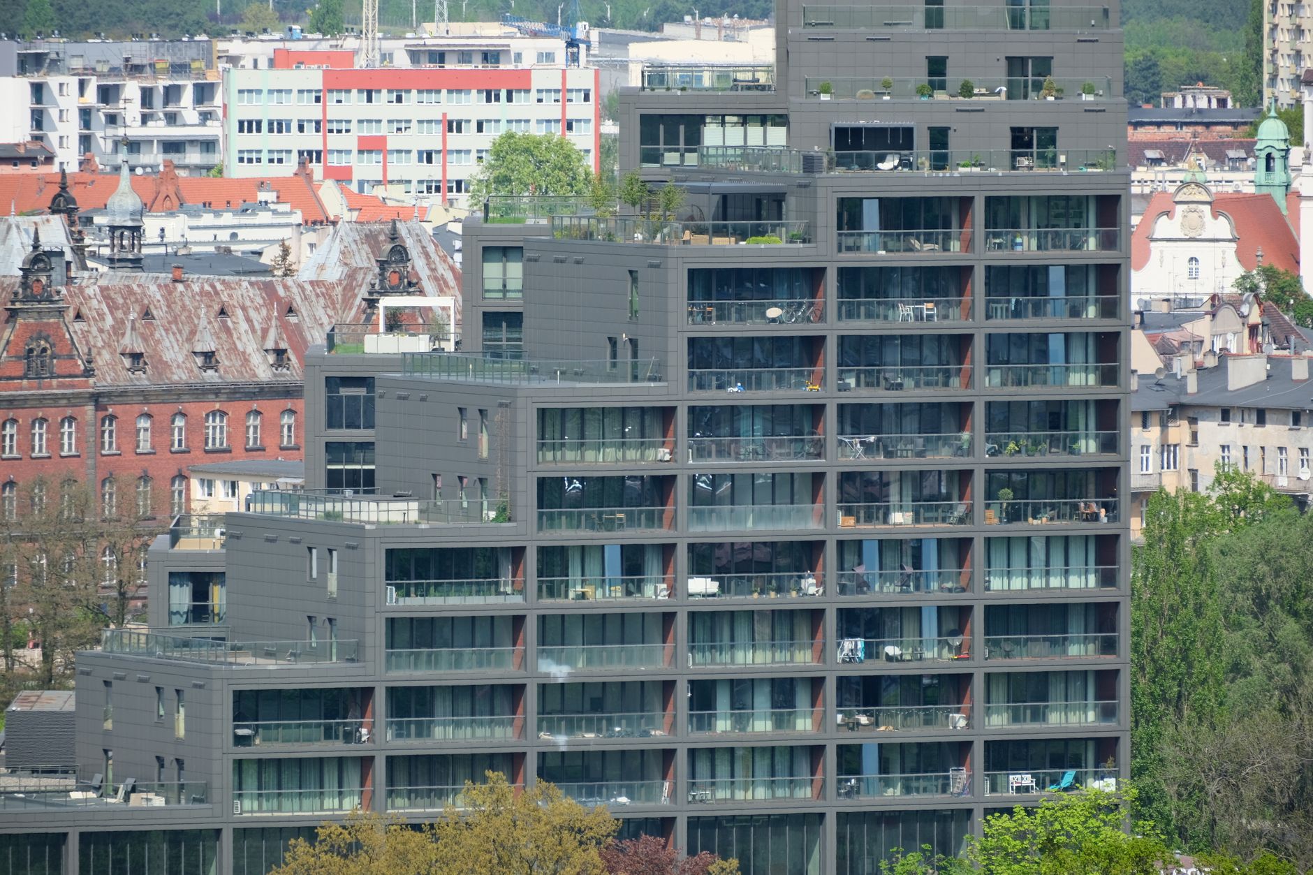 High-rise modern apartment building with a historic urban backdrop, showcasing mixed architectural styles.