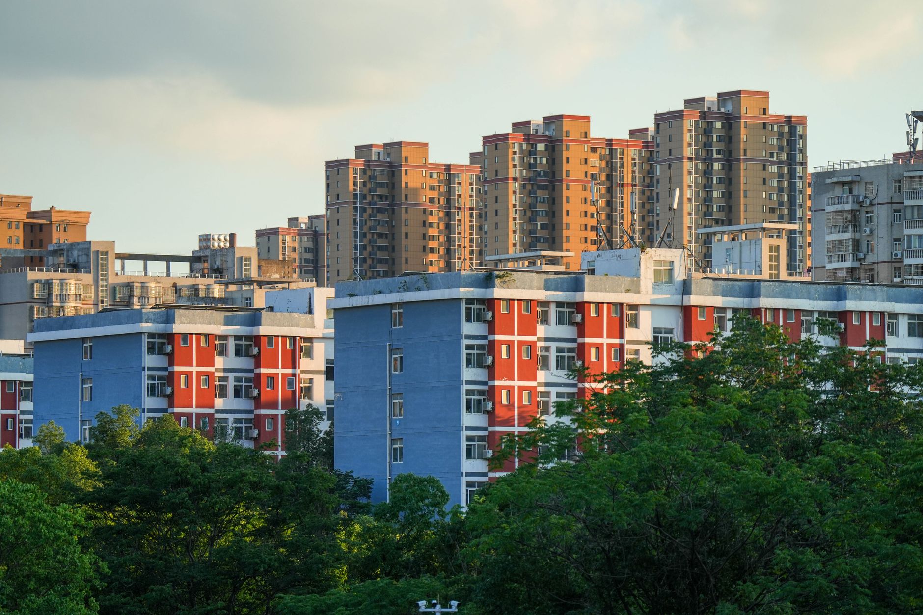 Urban landscape featuring high-rise residential buildings amidst lush greenery, captured during day.
