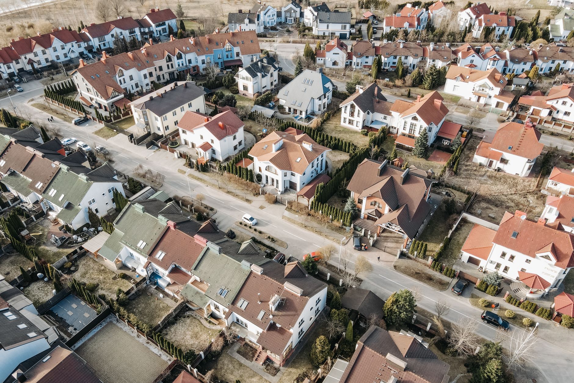 Drone view of a suburban residential area with houses and streets in daylight.