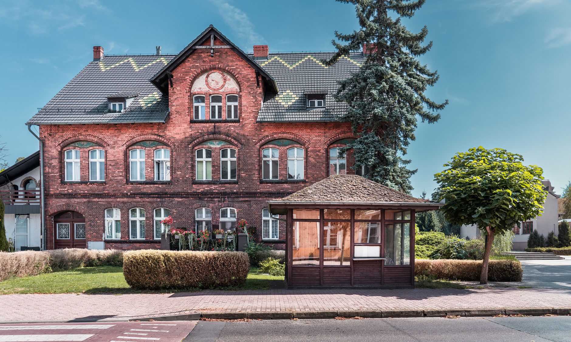 Charming historic brick building with lush greenery under a clear blue sky.