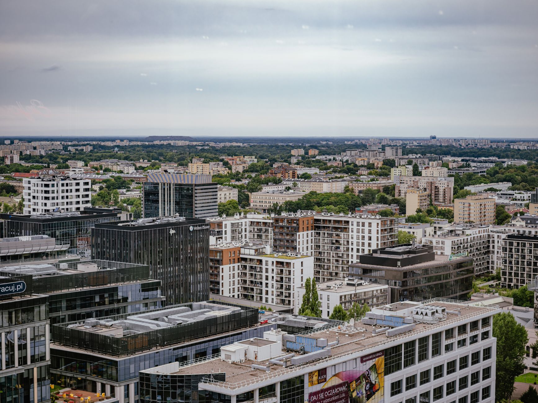 Aerial view of Warsaw showcasing modern and residential architecture against a lush backdrop.