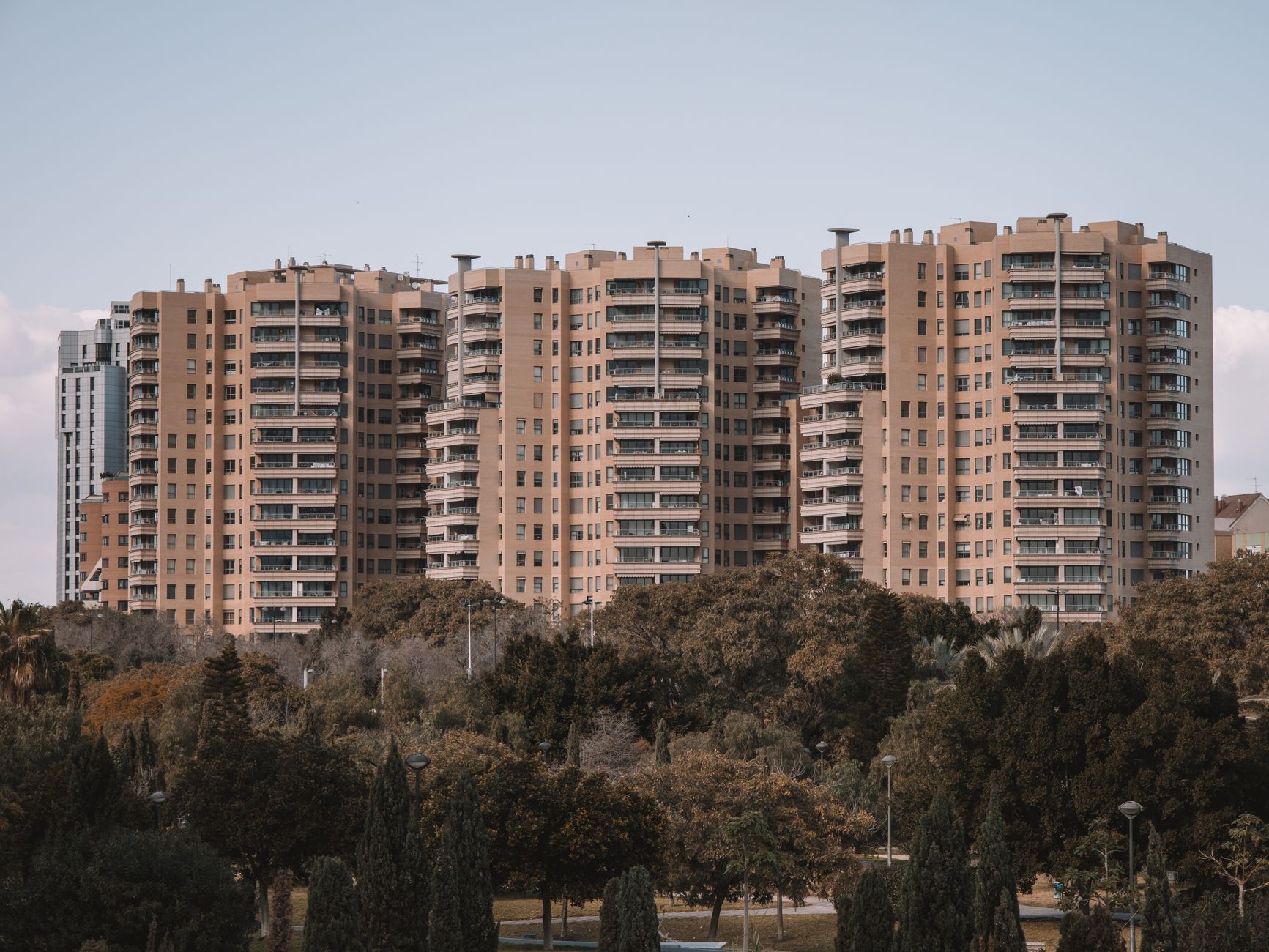 Seventeen-story apartment buildings in Valencia, Spain, with surrounding greenery under a clear sky.