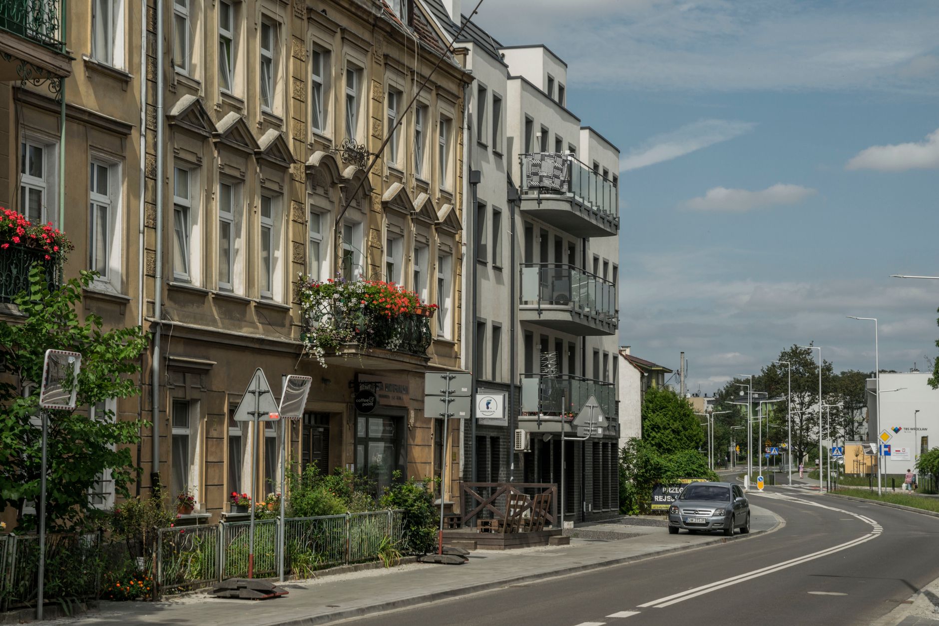 Street view of residential buildings and a car in Wrocław, showcasing city life.