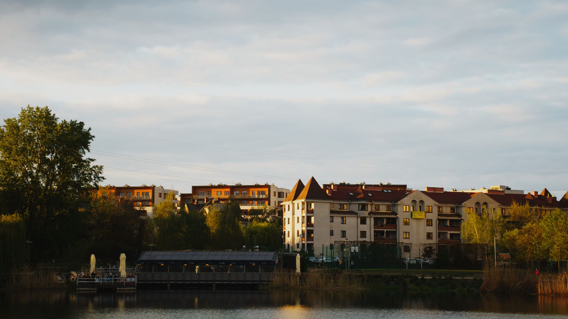 Charming Warsaw residential buildings nestled by a serene lake during a tranquil day.