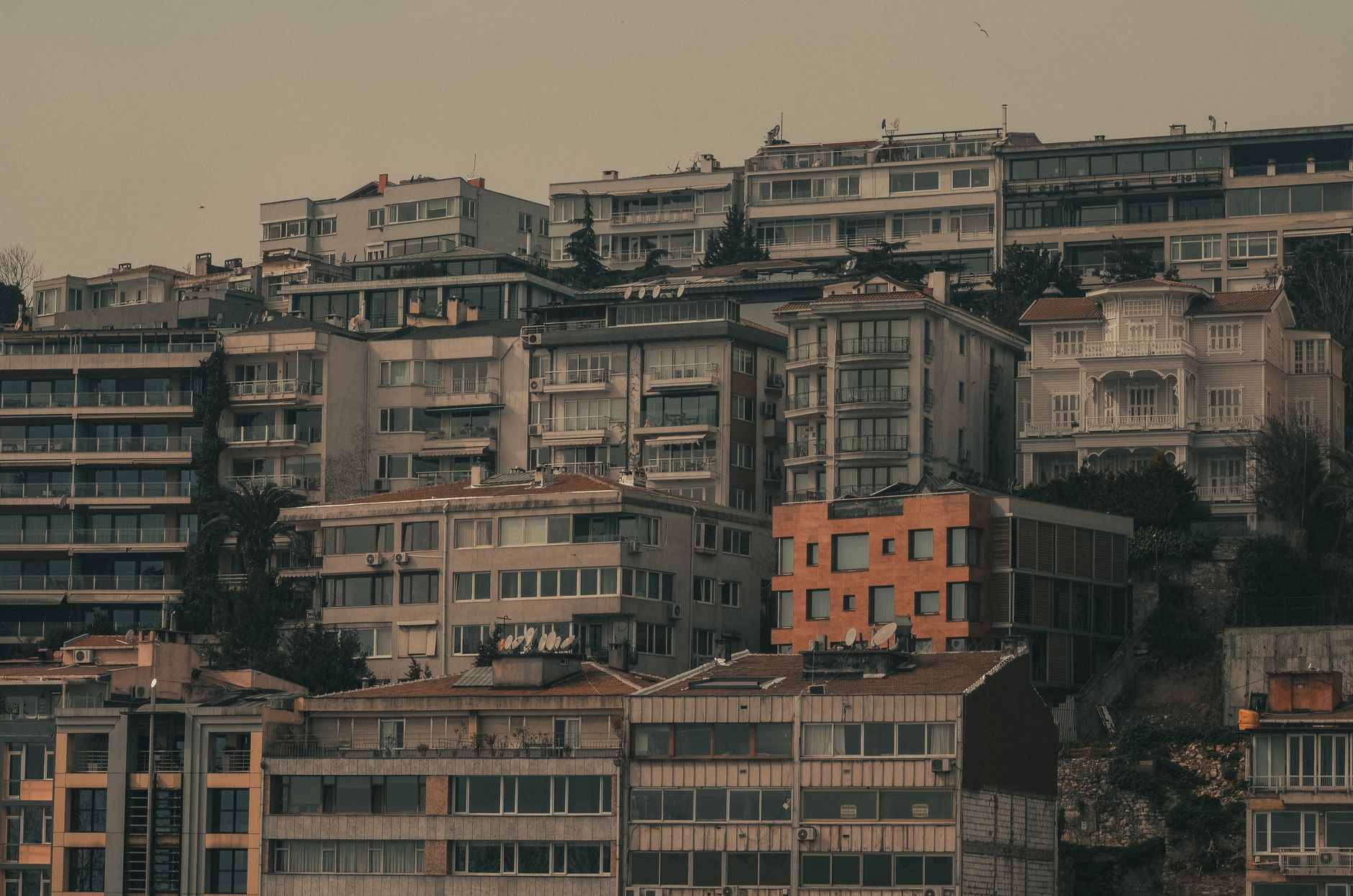 View of urban hillside apartment buildings under an overcast sky.