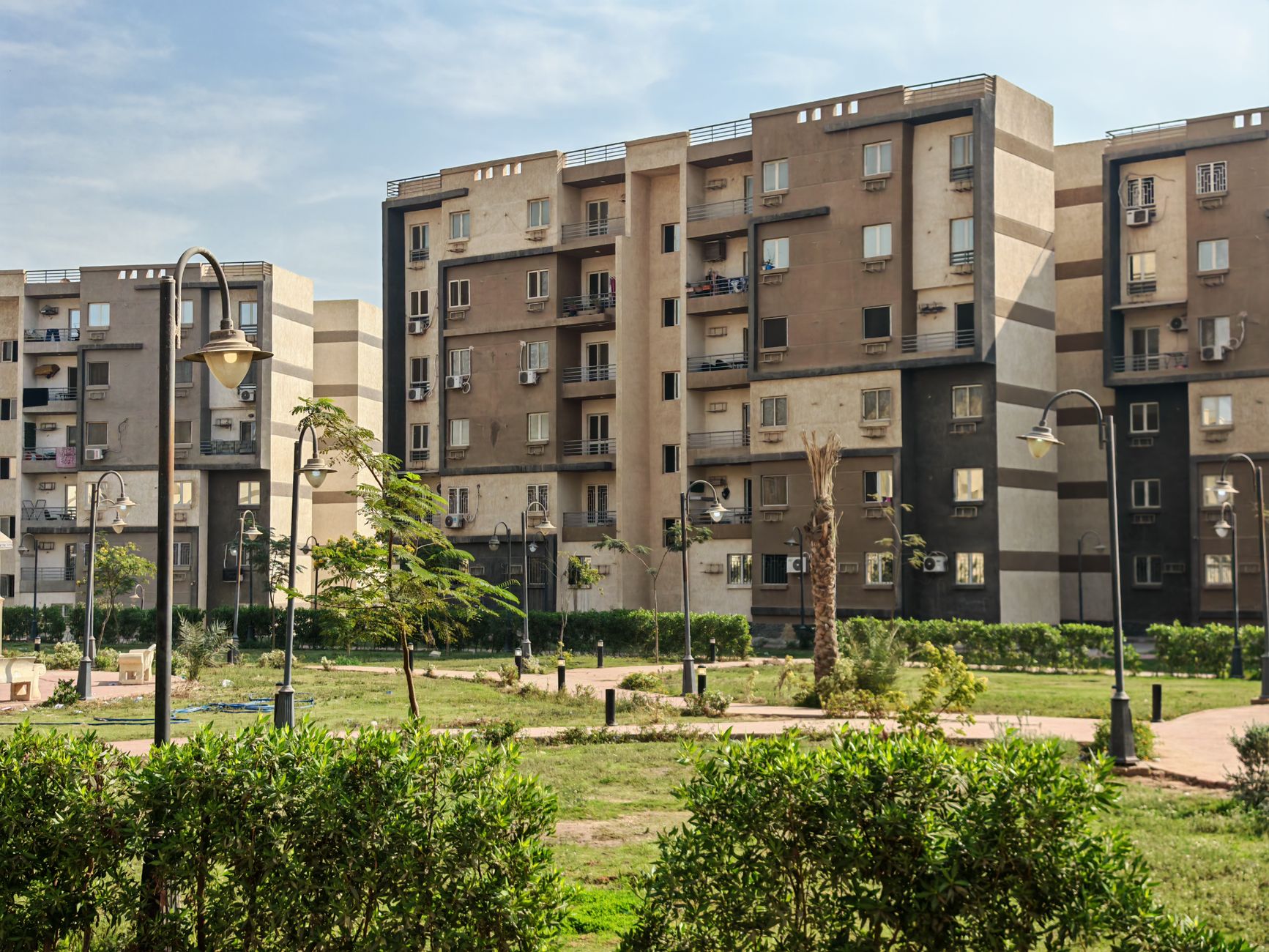A modern residential building complex with lush greenery and public park.