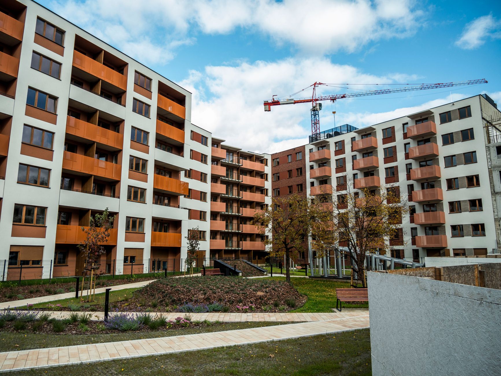 Newly built apartment complex with crane under blue sky, modern architecture.