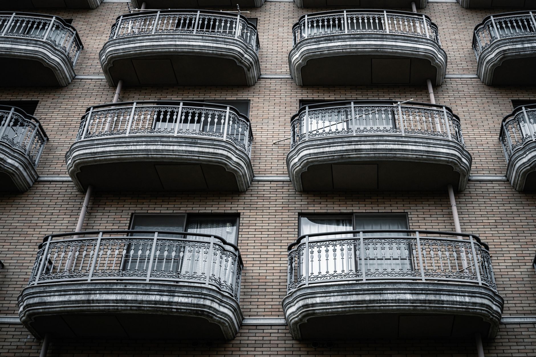 Symmetrical view of ornate balconies on a brick apartment building facade.