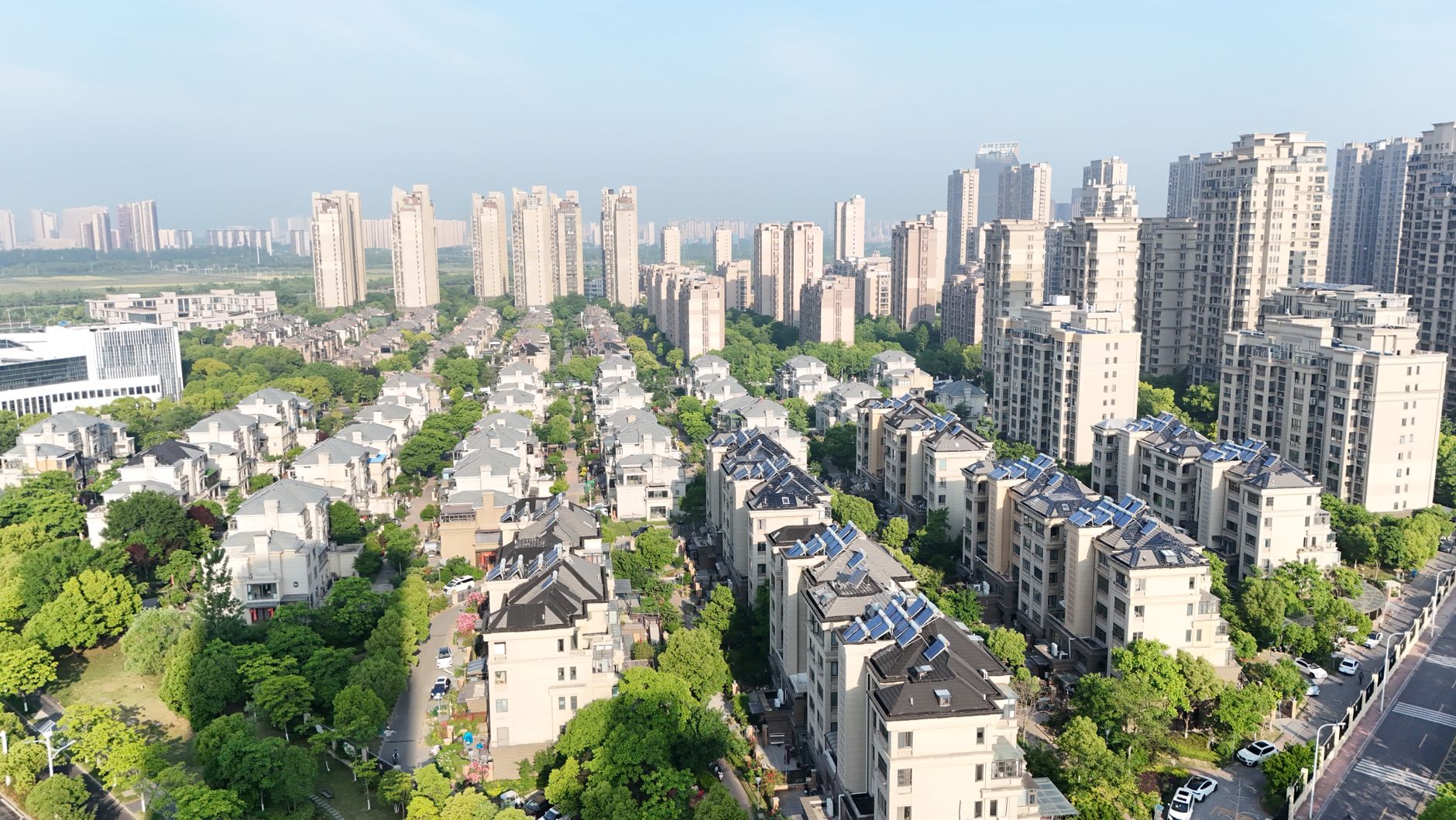 Aerial view of modern residential area with high-rise apartments and greenery on a sunny day.