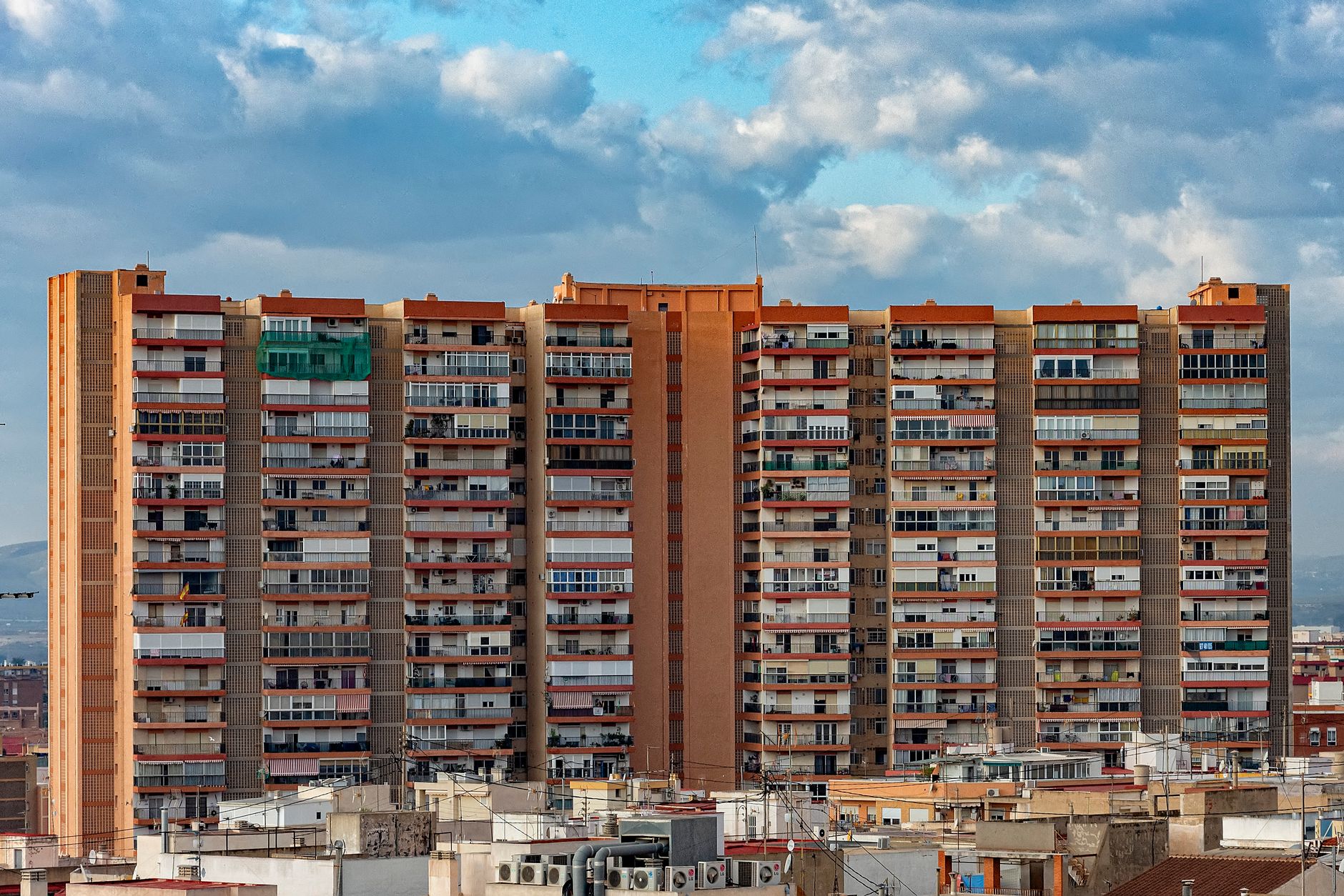 A towering residential building under a cloudy sky in Alicante, Spain.