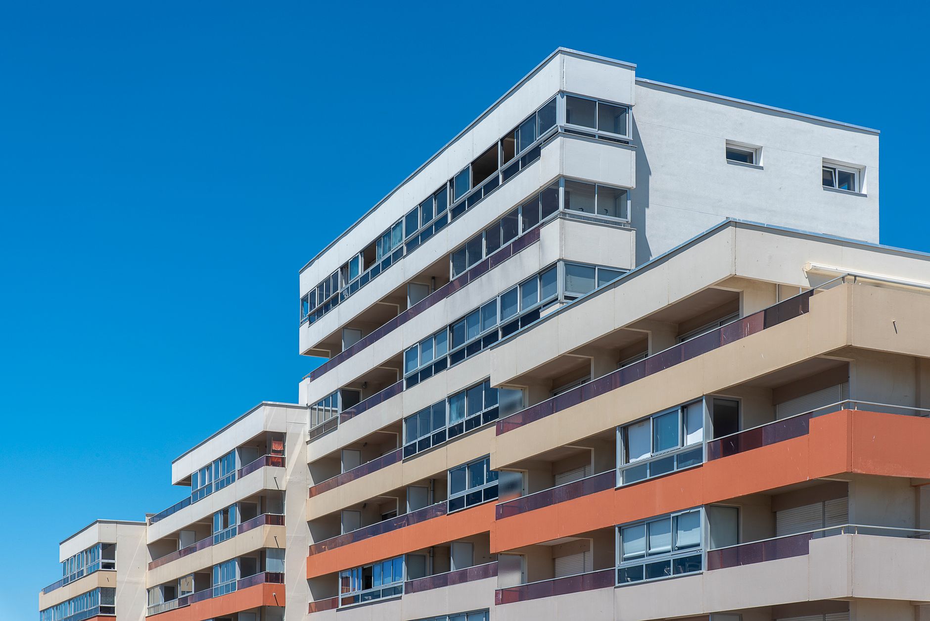 Contemporary multi-story apartment buildings with balconies under a clear blue sky, showcasing modern architecture.