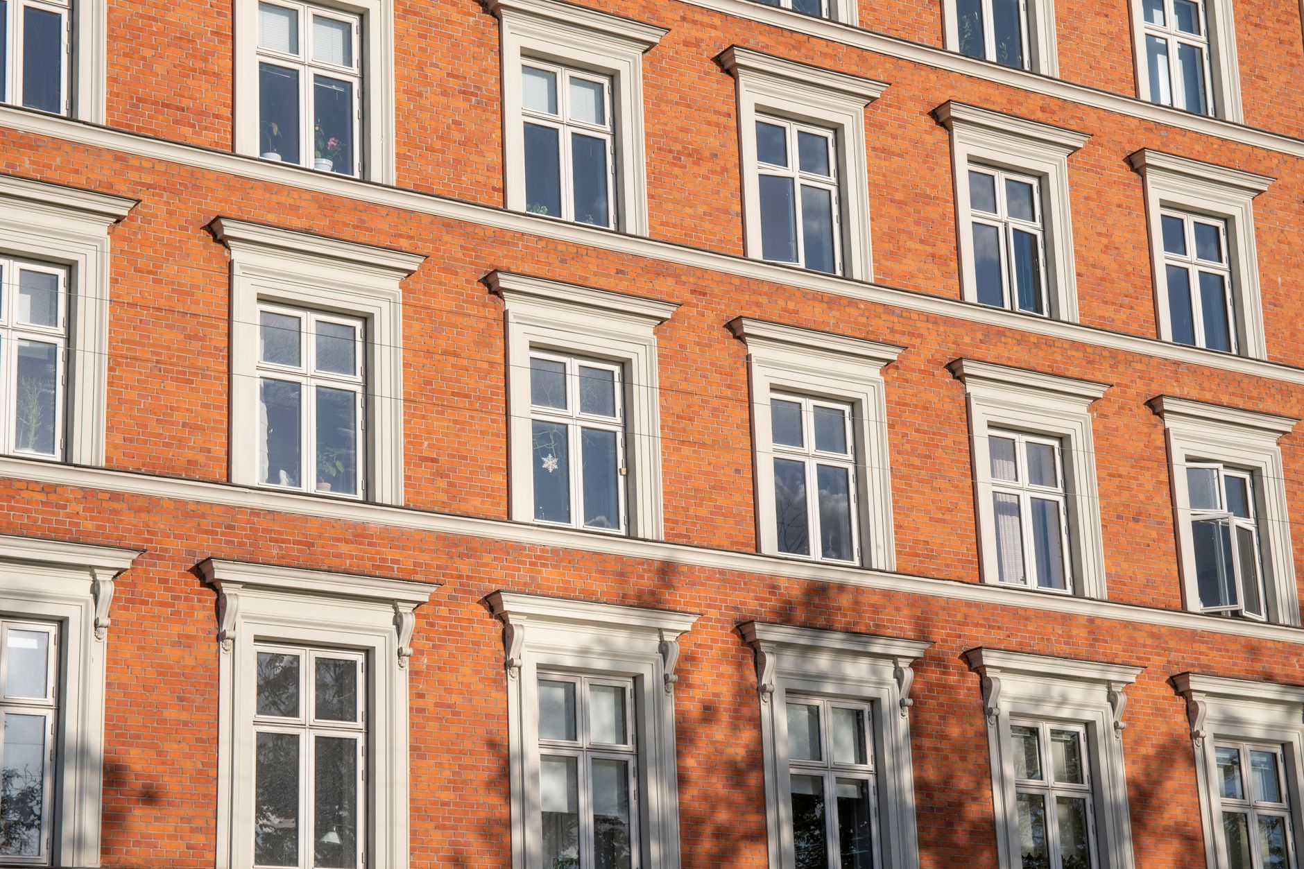 Low angle view of traditional brick apartment building with white framed windows in Copenhagen.
