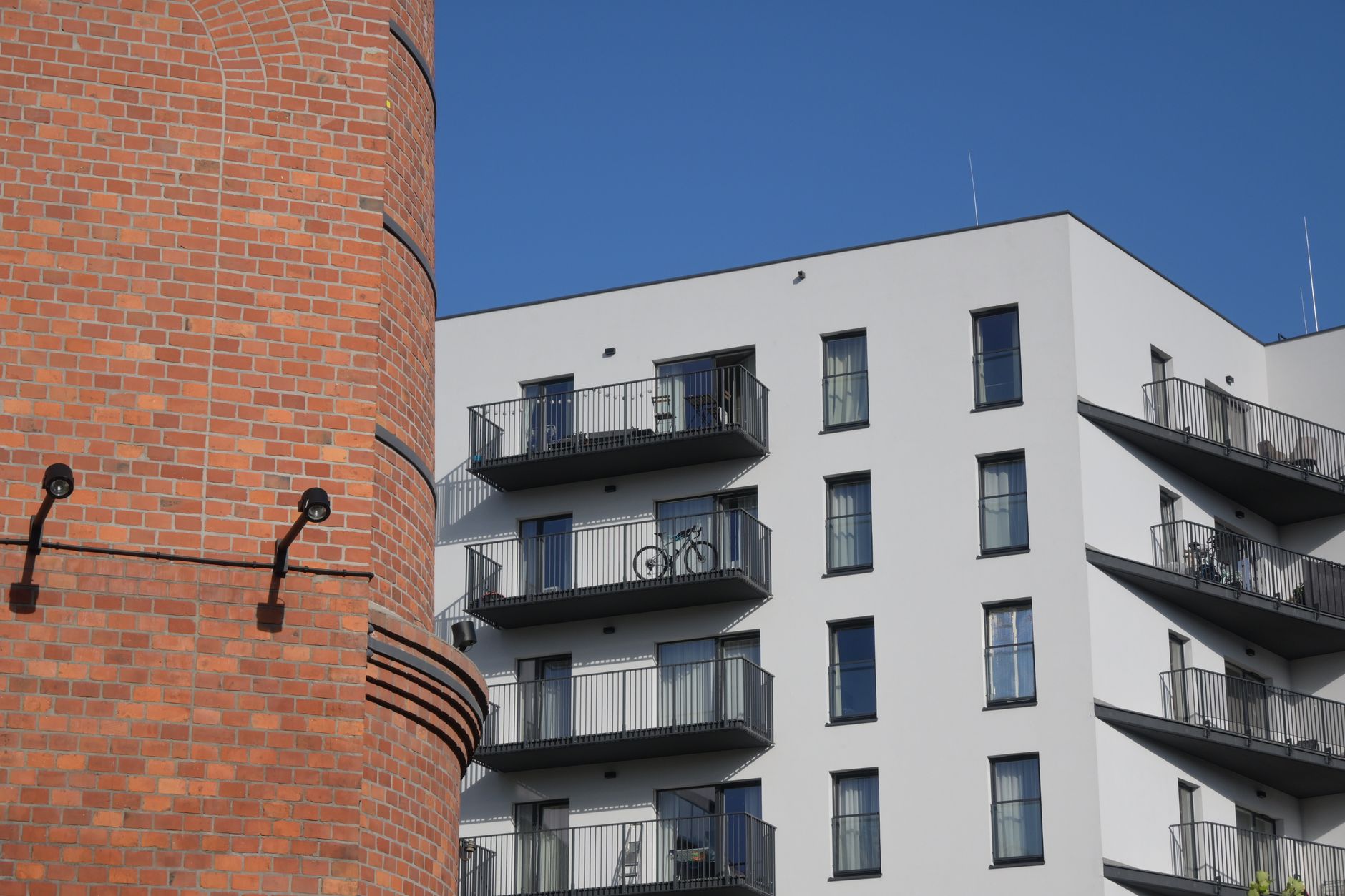 A modern apartment building next to a traditional brick structure in Warsaw, Poland.