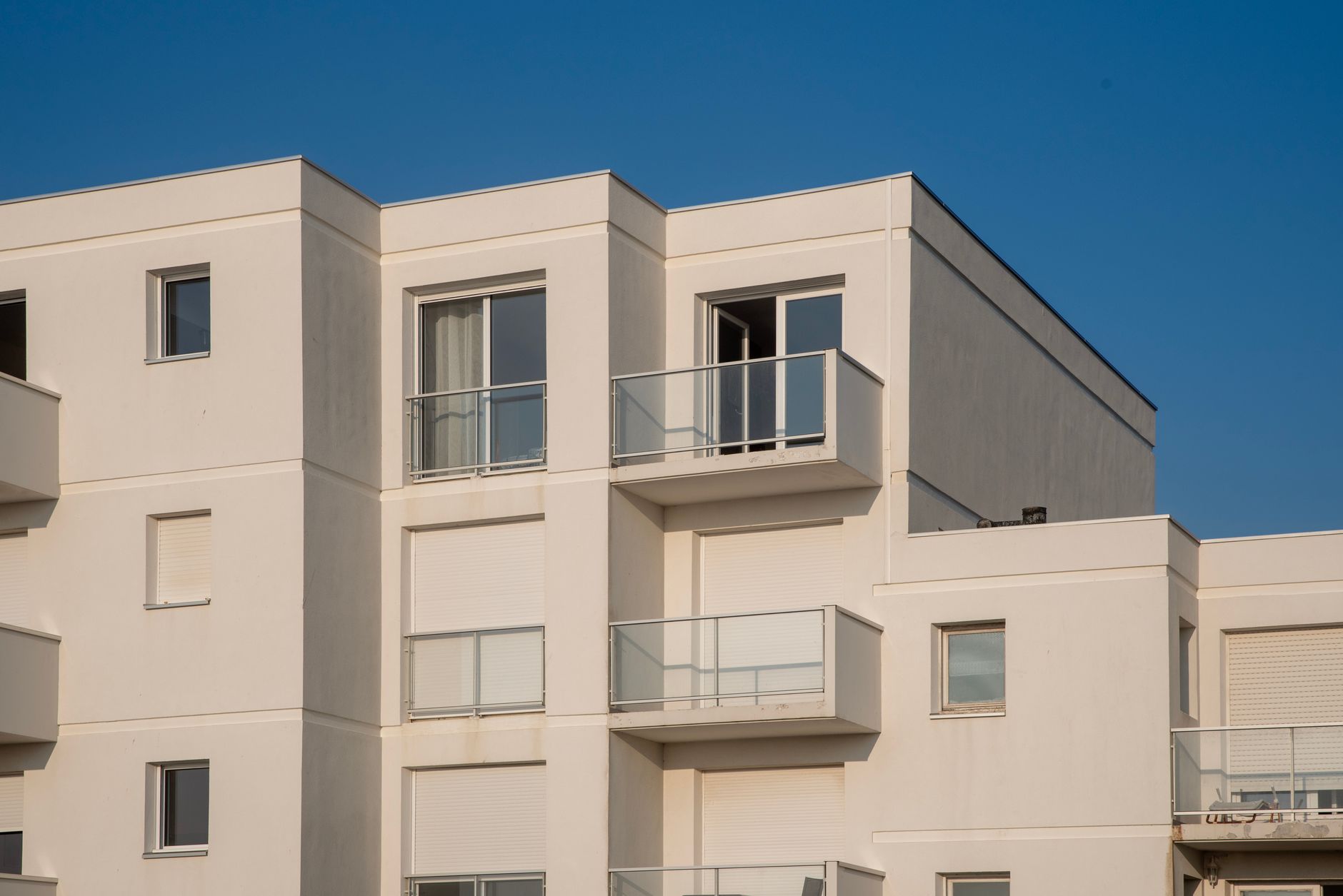 A view of a contemporary white apartment complex under a clear blue sky.