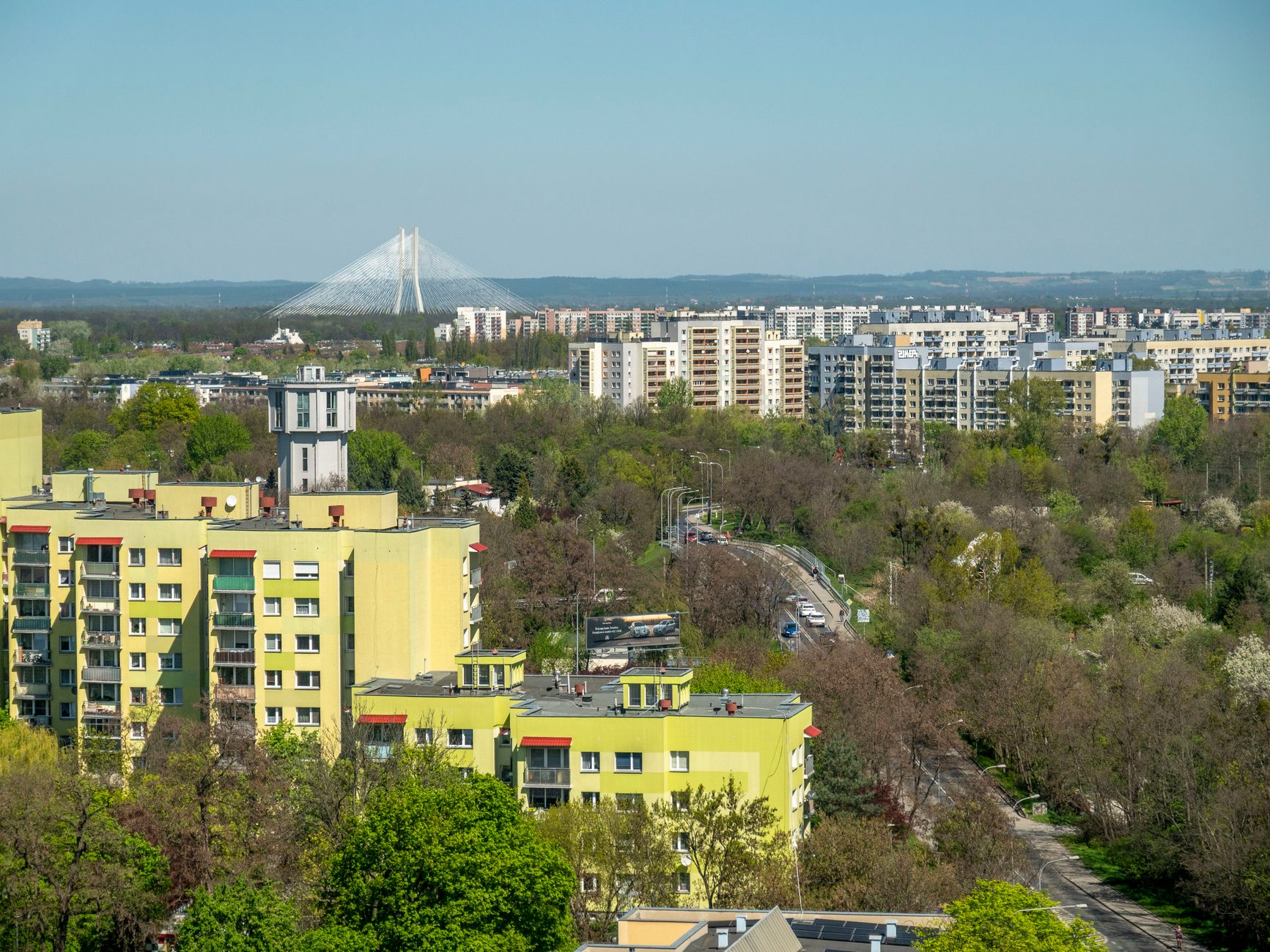 Aerial view of Wrocław cityscape highlighting residential buildings and a distinct bridge in the distance.