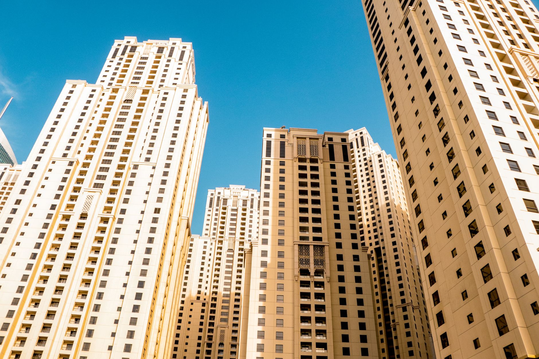 High-rise residential buildings in a modern cityscape contrast with a clear blue sky.