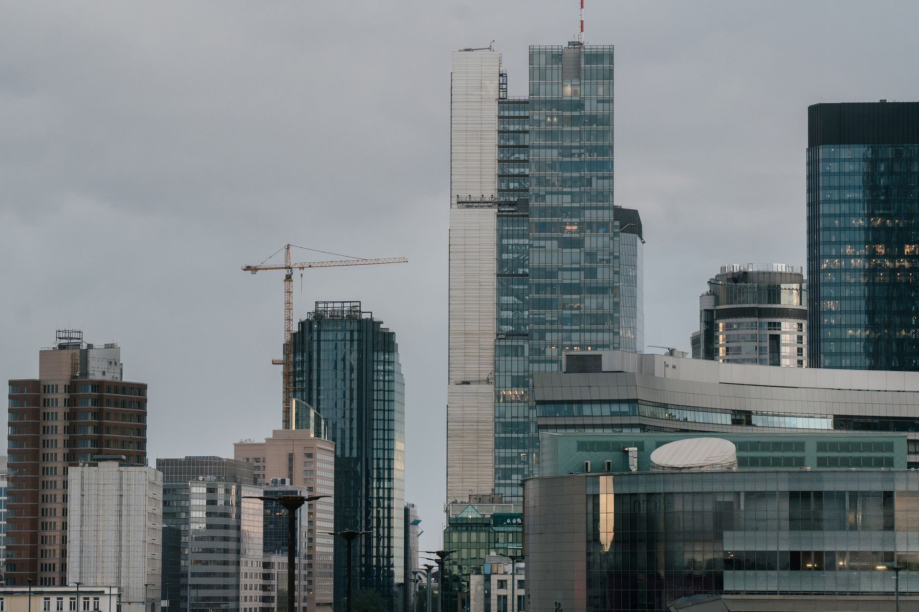 A view of Warsaw skyline featuring contemporary skyscrapers and construction cranes at daytime.