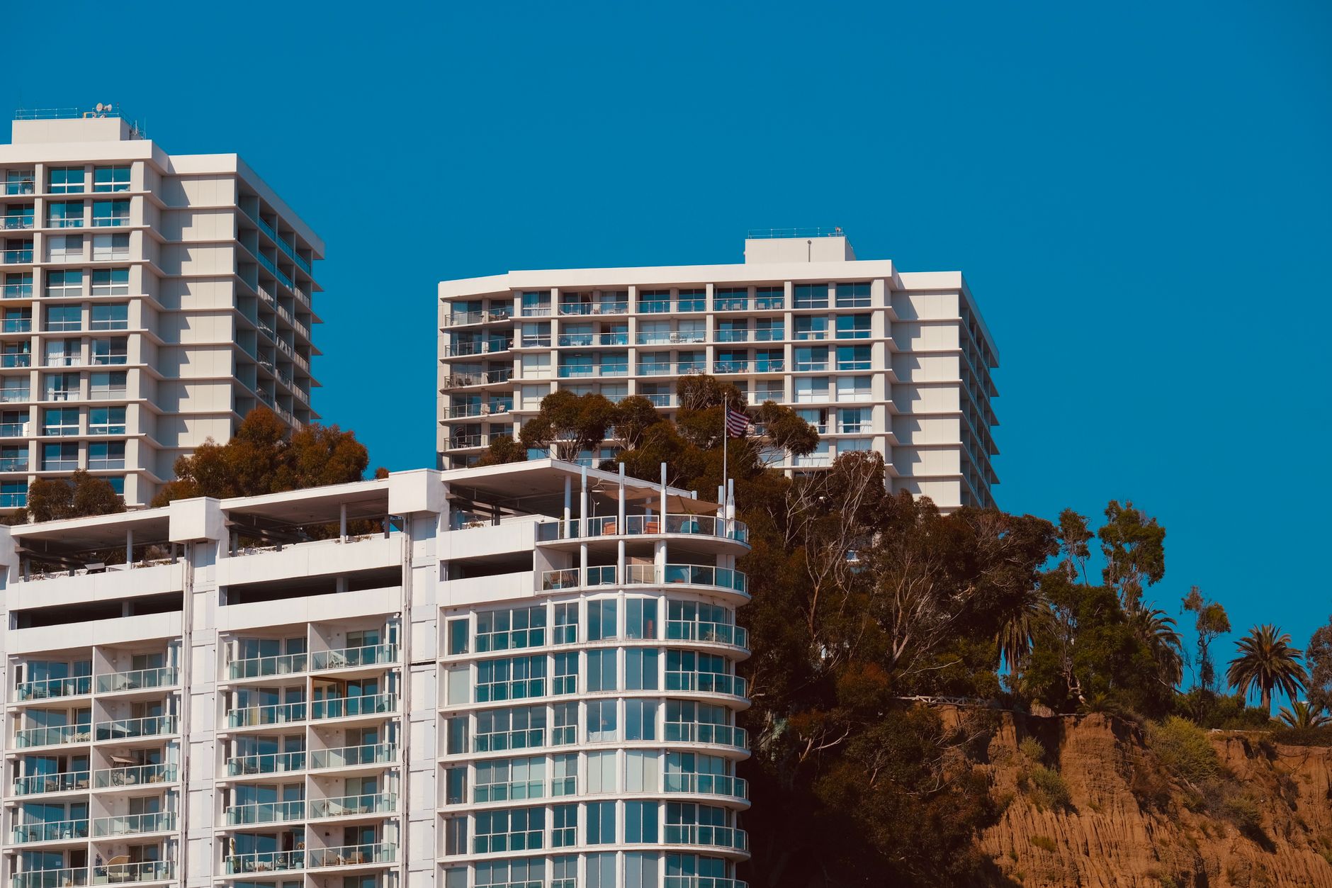 Contemporary high-rise apartments with lush greenery against a clear sky.