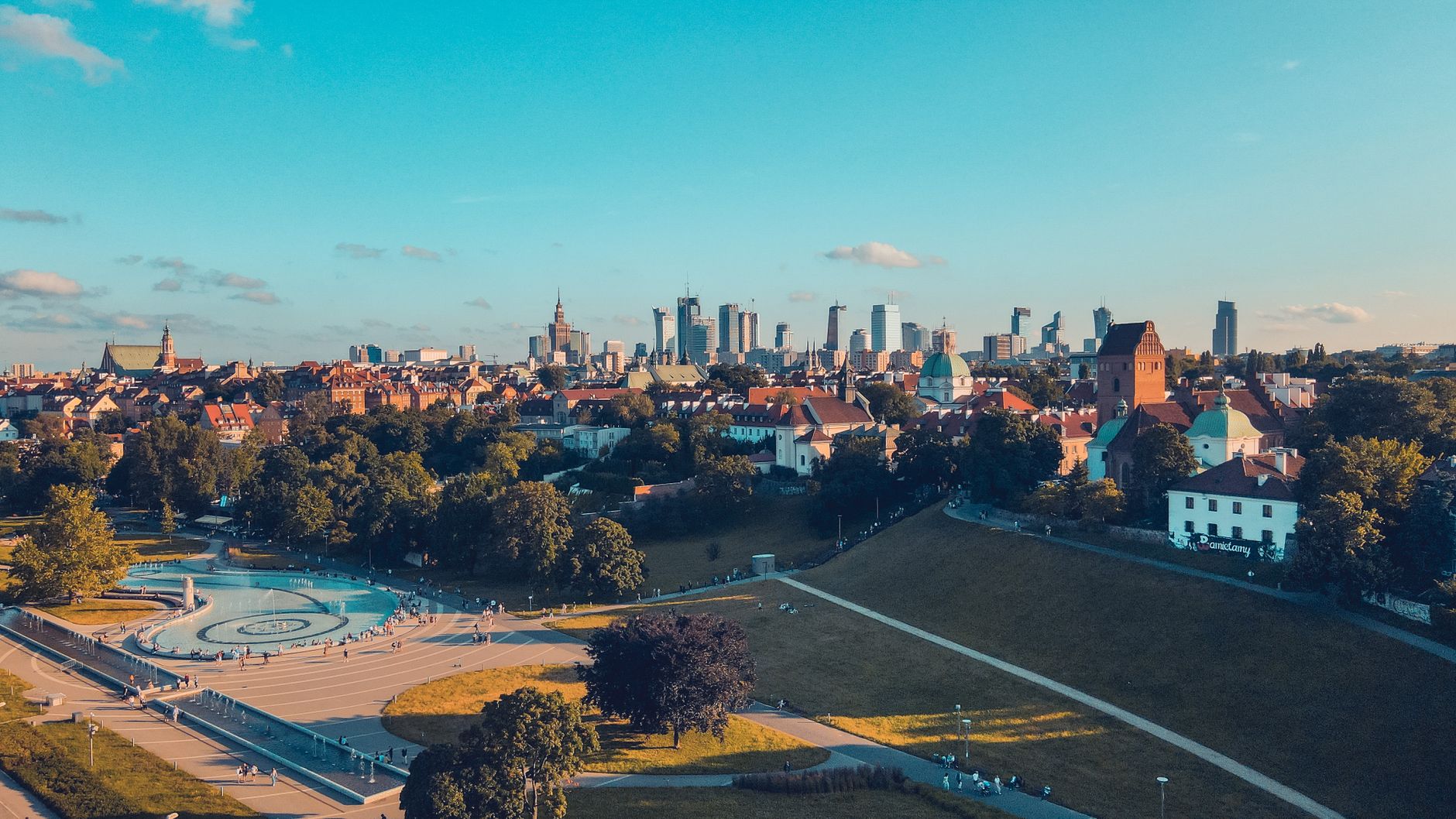 Stunning aerial shot of Warsaw skyline and park under a bright blue sky.