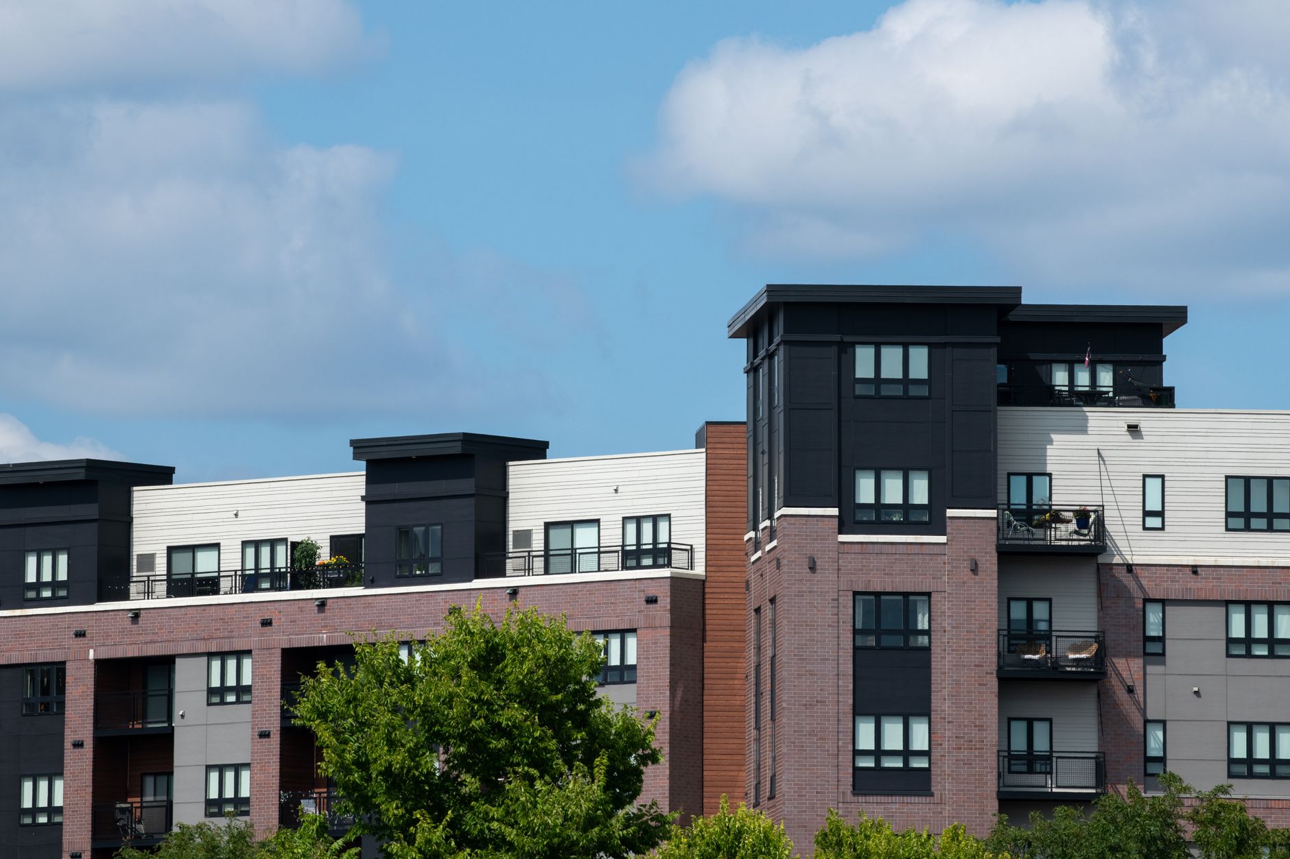 Contemporary urban apartment complex with brick and panel design under clear blue skies.
