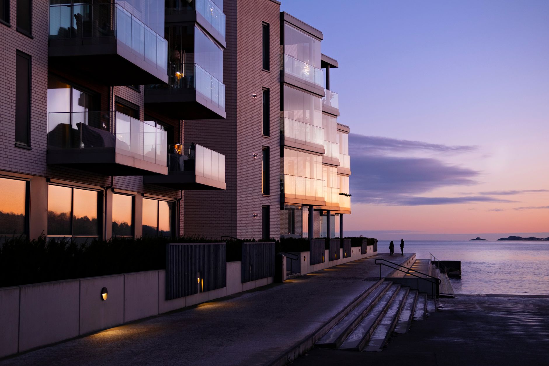 Contemporary apartment building overlooking the seacoast at sunset, capturing a serene evening ambiance.