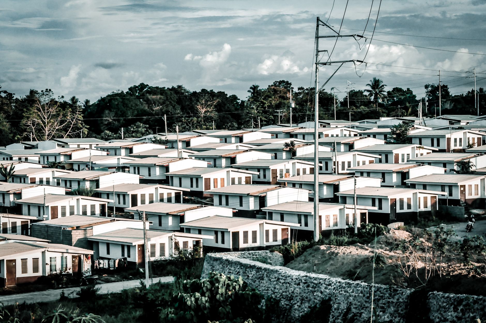 Aerial shot of a modern suburban housing area with identical homes under a cloudy sky.