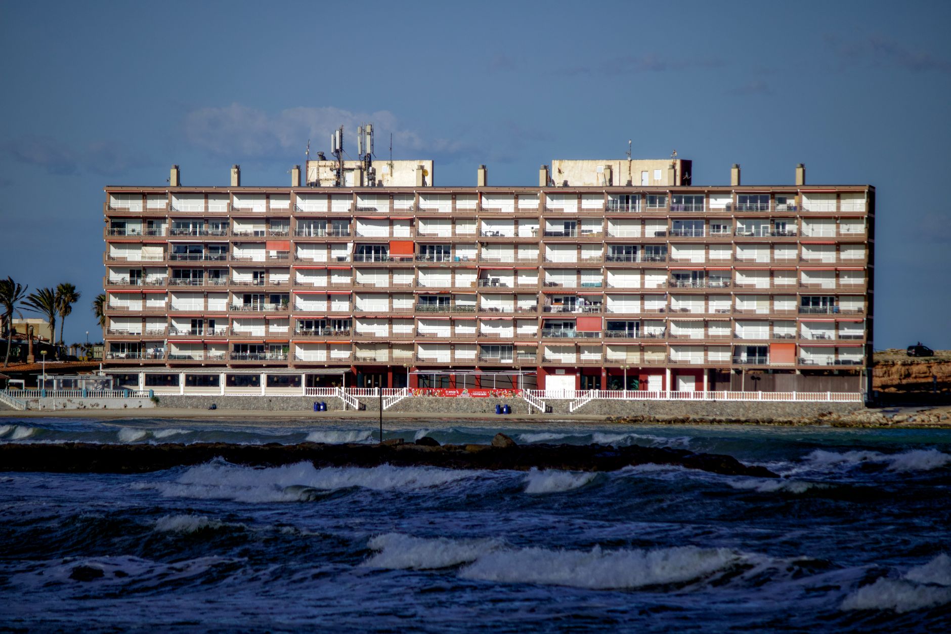 A modern apartment building by the sea in Torrevieja, Spain, under clear skies.