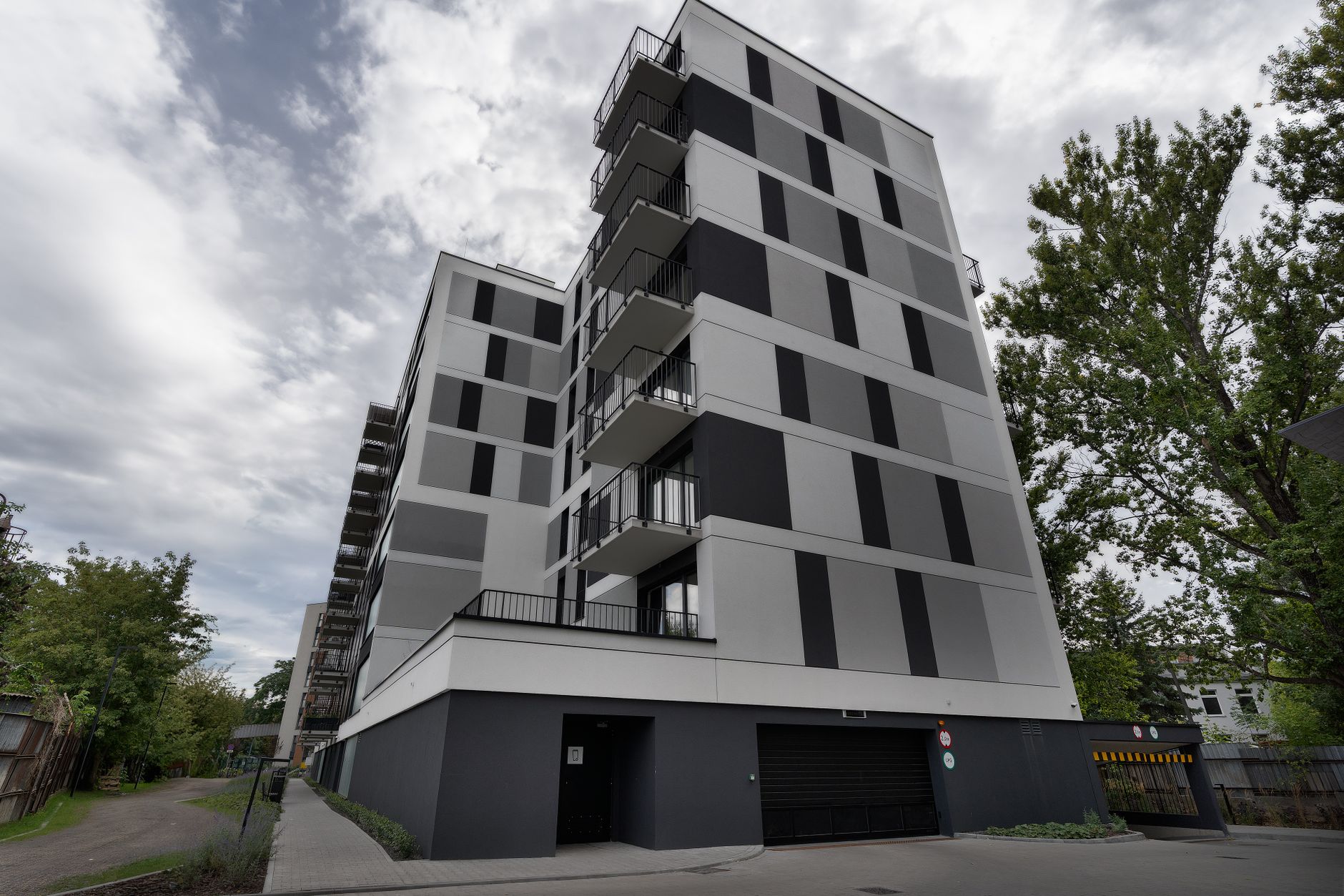 Contemporary urban apartment building with balconies under cloudy sky.
