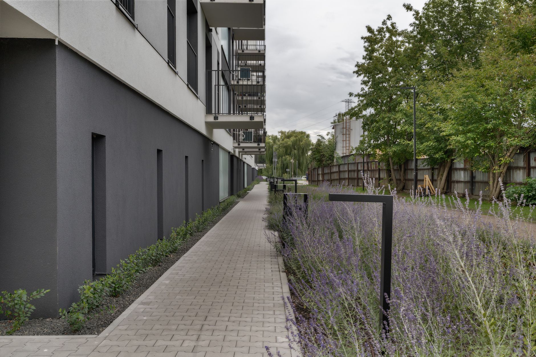 Exterior view of a modern apartment building with a landscaped garden path.