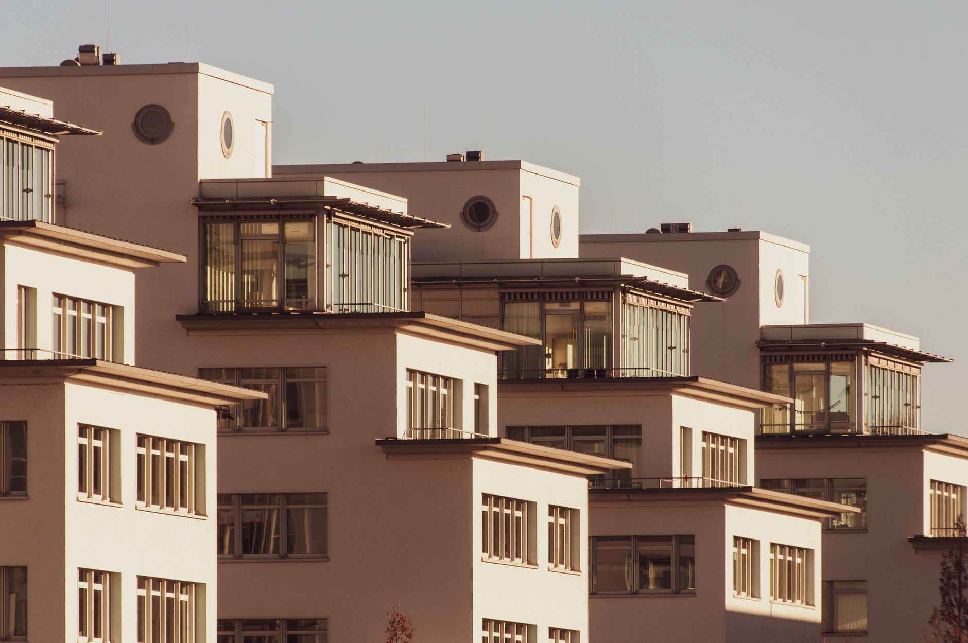 Explore modern white apartment blocks with stylish glass features, bathed in soft daylight.