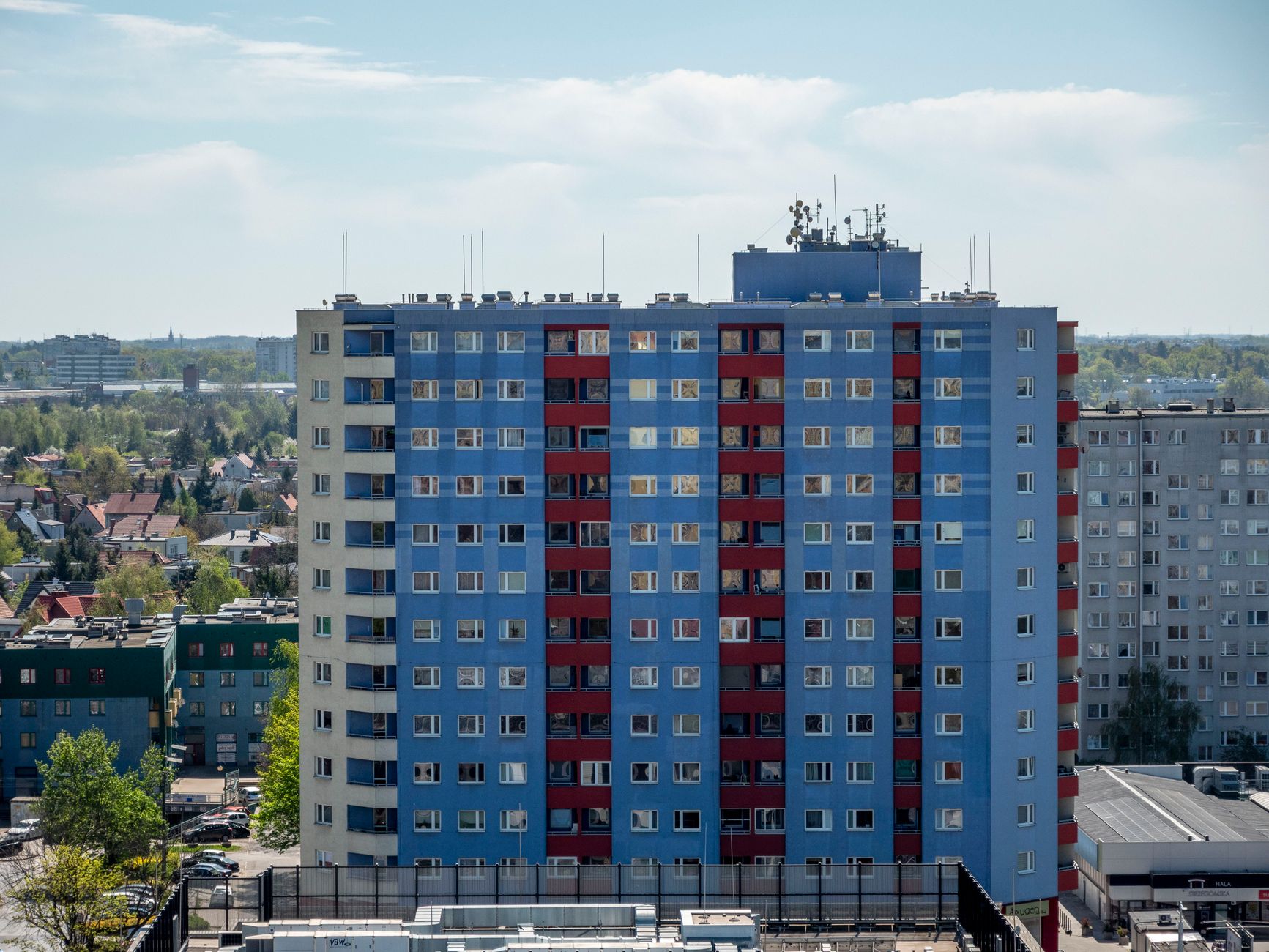 Bright blue and red apartment building in Wrocław, Poland, with surrounding urban scenery.