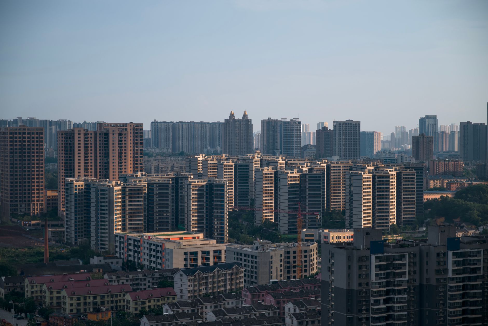 Aerial view of a modern city skyline with numerous high-rise apartment buildings under a clear sky.