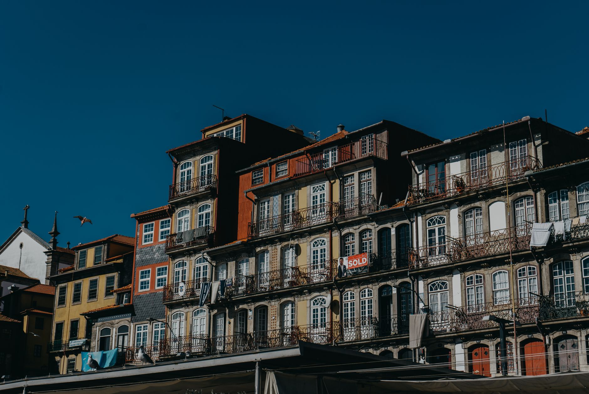 Beautiful facade of historic townhouses in a European city under a clear blue sky, highlighting urban architecture.