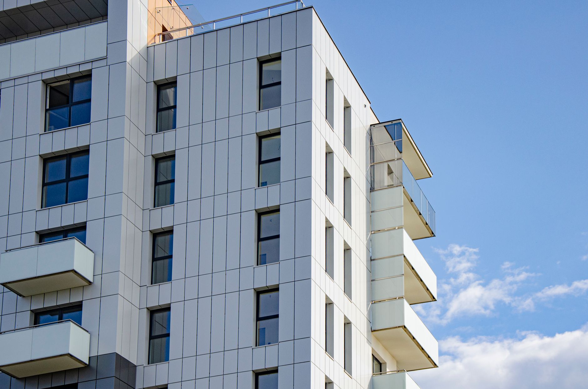 A contemporary apartment facade with balconies against a clear blue sky in Rzeszów, Poland.