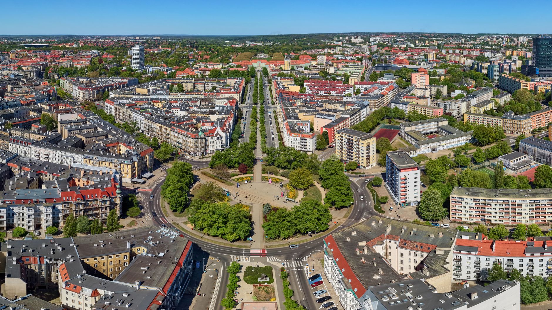 A stunning aerial view of Szczecin, showcasing its urban structure, residential buildings, and greenery on a sunny day.