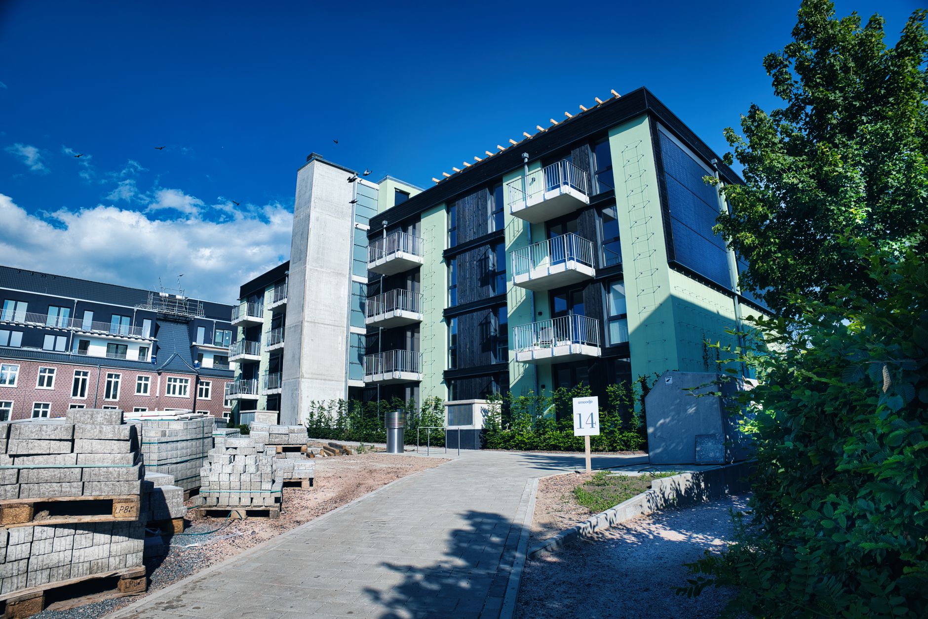 A contemporary apartment building with green accents and balconies in an urban setting.