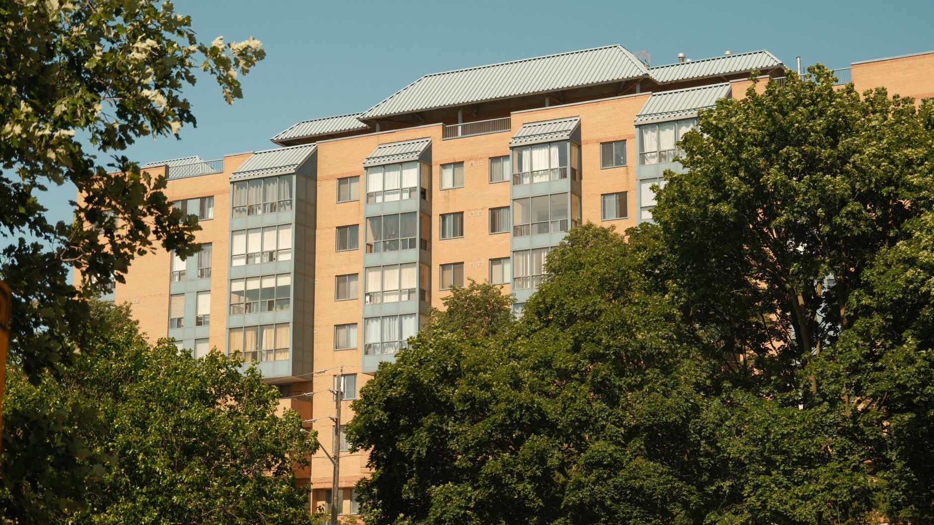 A bright view of a modern apartment building surrounded by trees in Oshawa, Ontario.