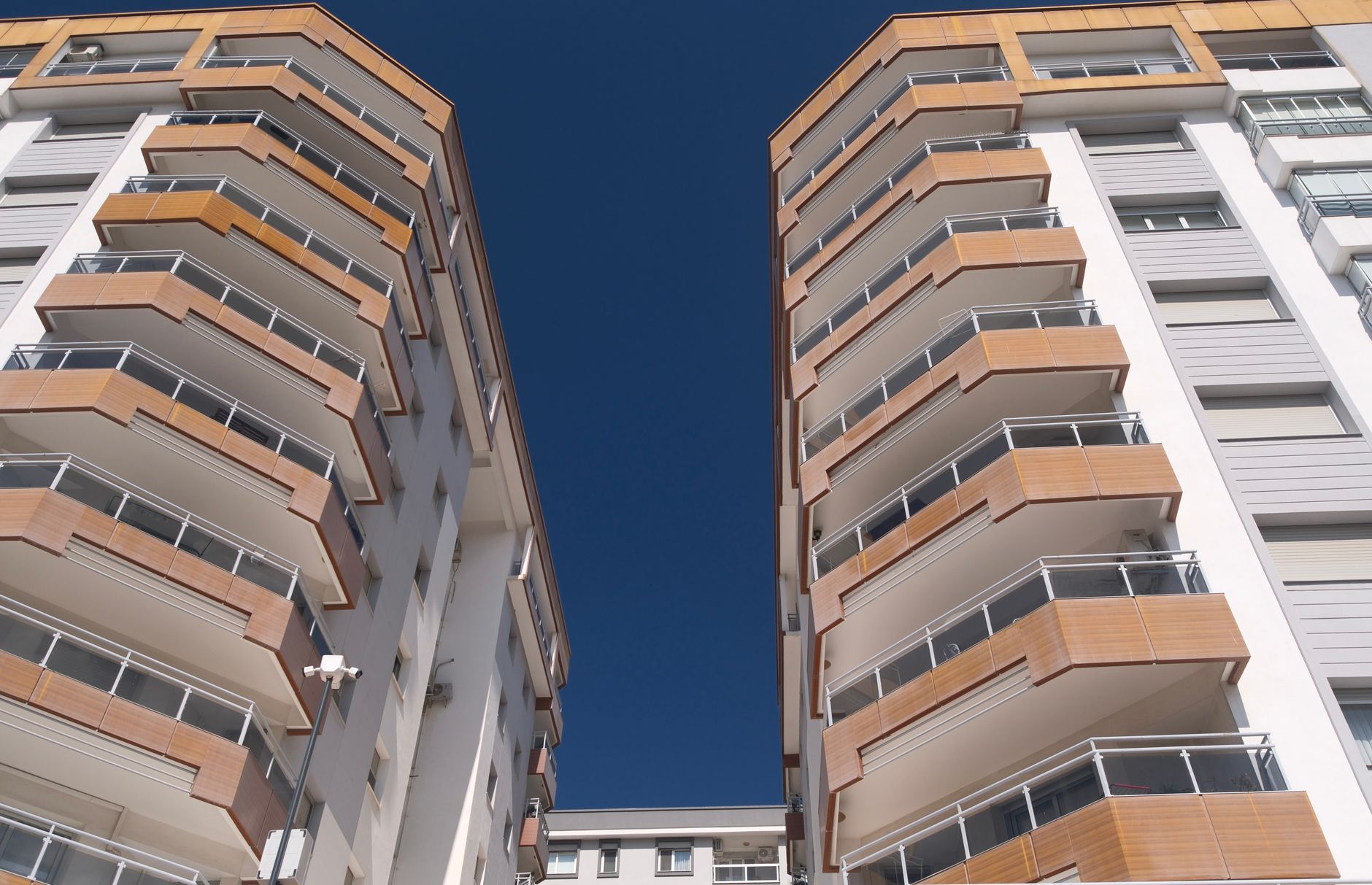 Upward view of two modern apartment buildings with a clear blue sky in İzmir, Türkiye.