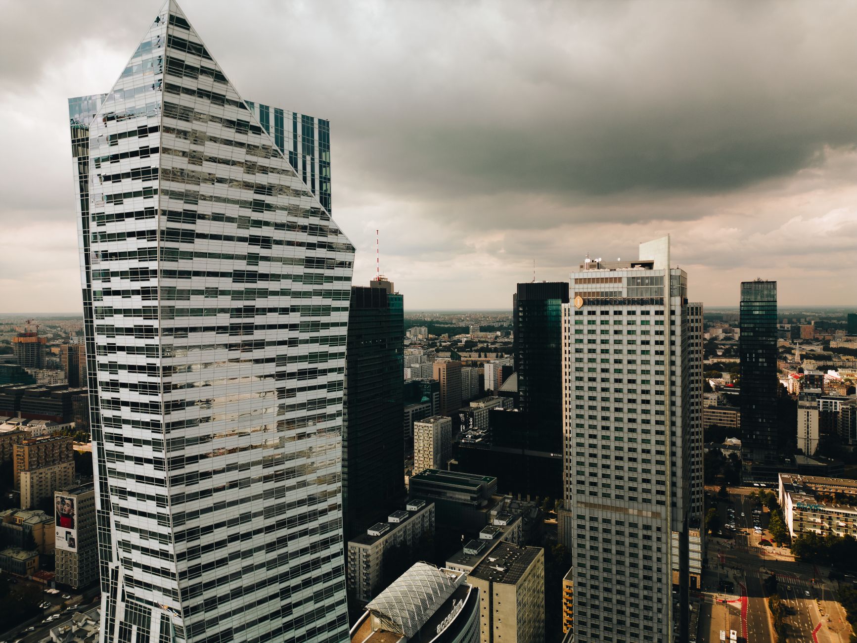 Aerial view of the modern Warsaw skyline with striking skyscrapers and dramatic clouds.