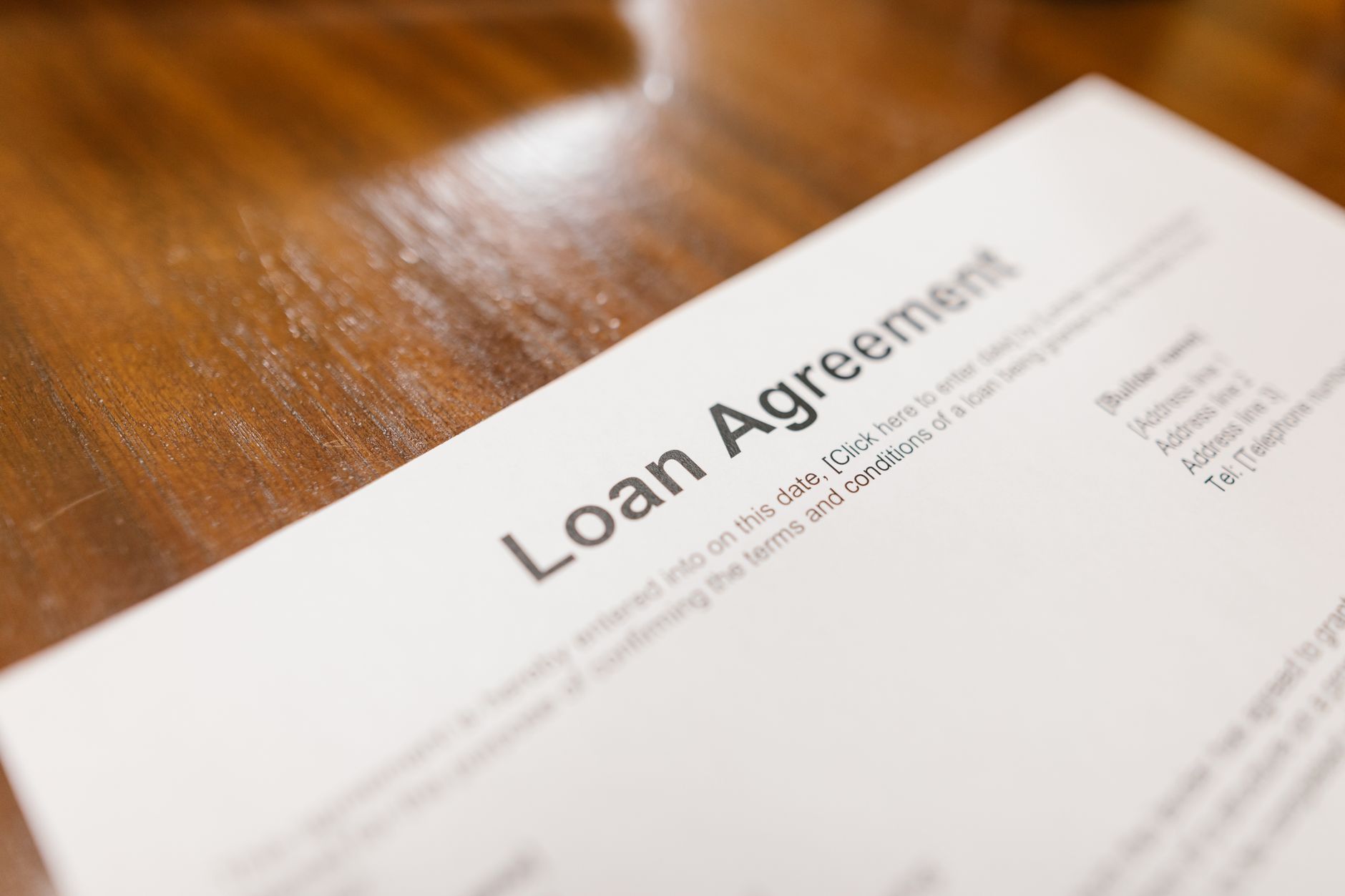 Detailed loan agreement document close-up on a wooden table representing legal and financial concepts.