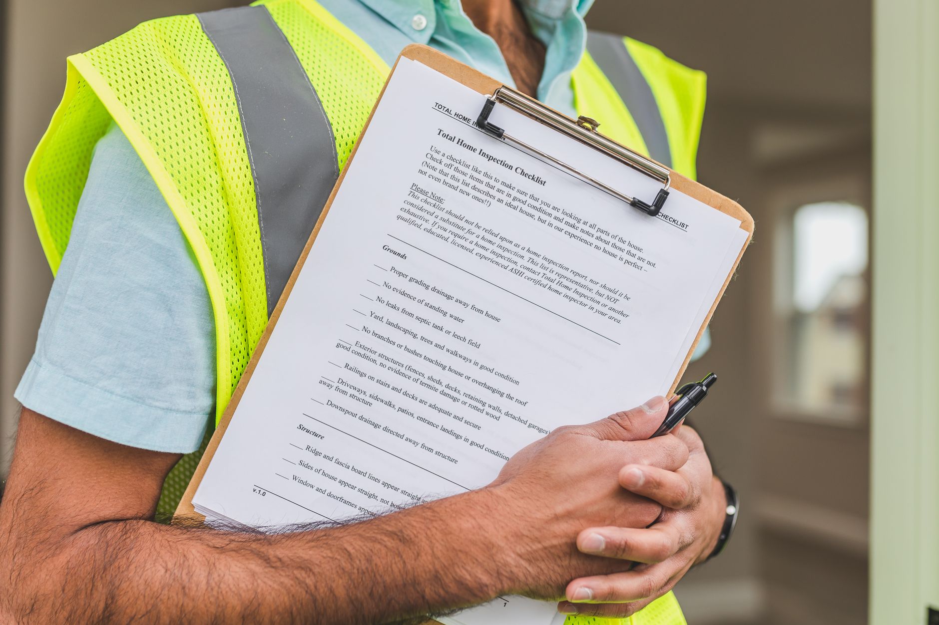 Close-up of home inspector holding a checklist on a clipboard with a pen.
