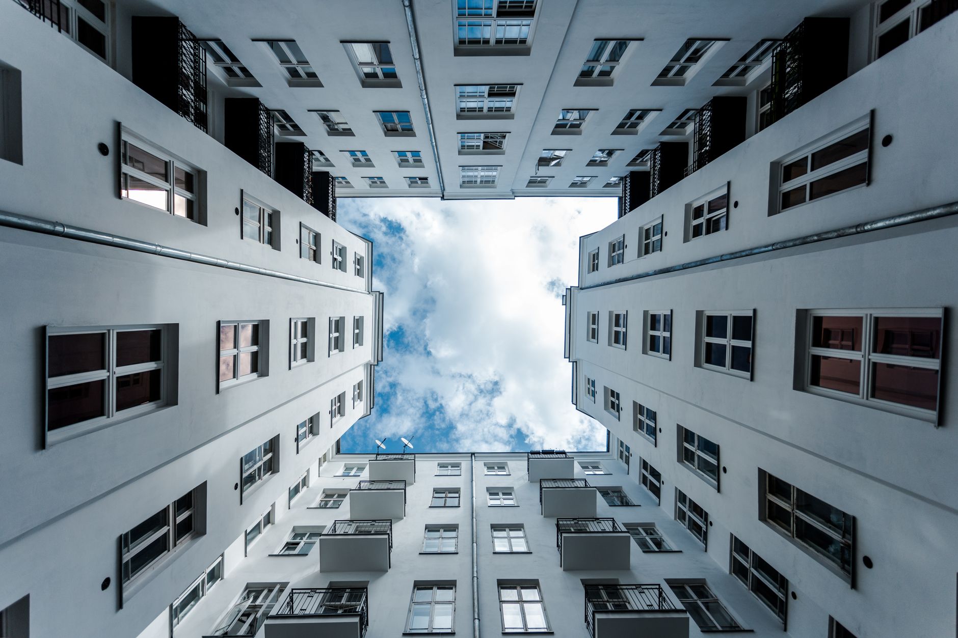Upward view of a modern apartment courtyard in Warsaw, showcasing architectural symmetry.