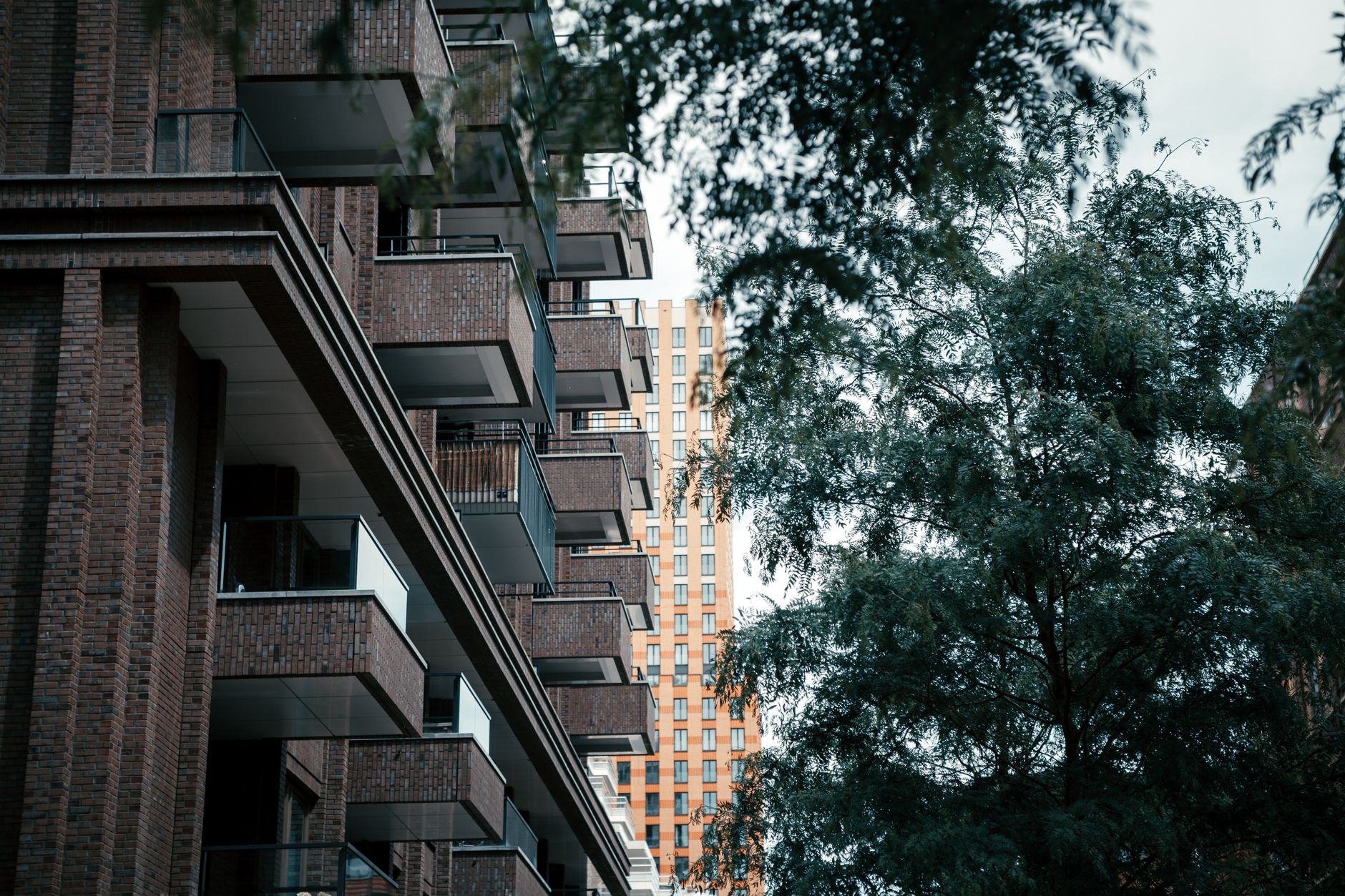 Low-angle view of brick residential buildings with lush greenery.